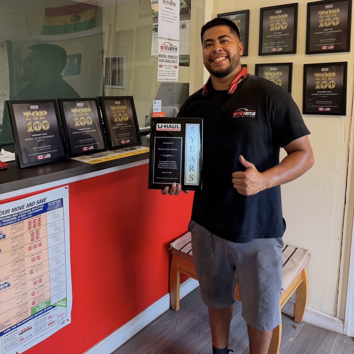 Steven Arias, owner of Steven's Auto Services, holding his U-Haul five-year service plaque