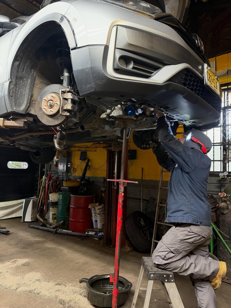 Mechanic working under a raised SUV in the bay